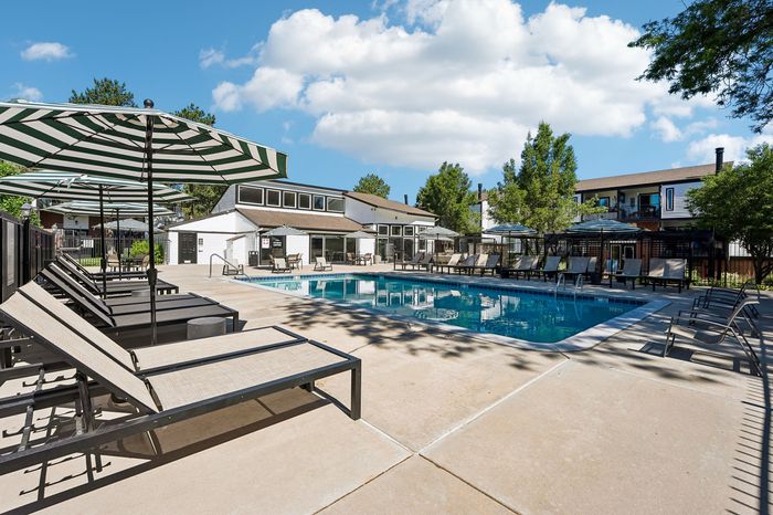 Inviting outdoor pool area with stylish loungers and umbrellas, perfect for relaxation and entertainment under a bright blue sky.