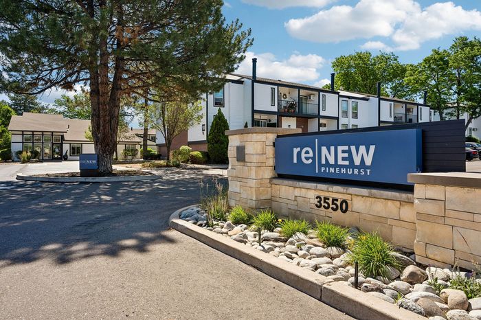 Inviting exterior of ReNew Pinehurst apartments, featuring modern architecture surrounded by lush greenery and a welcoming entrance.