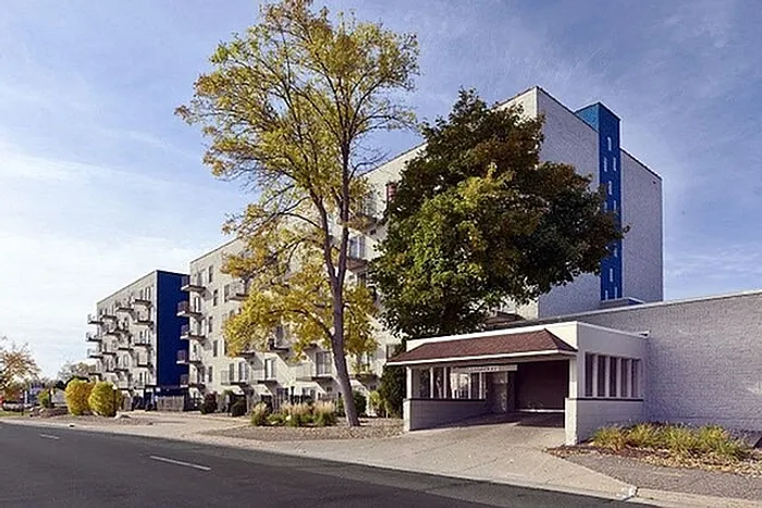 Charming apartment building with modern facade, surrounded by lush trees and serene landscaping.