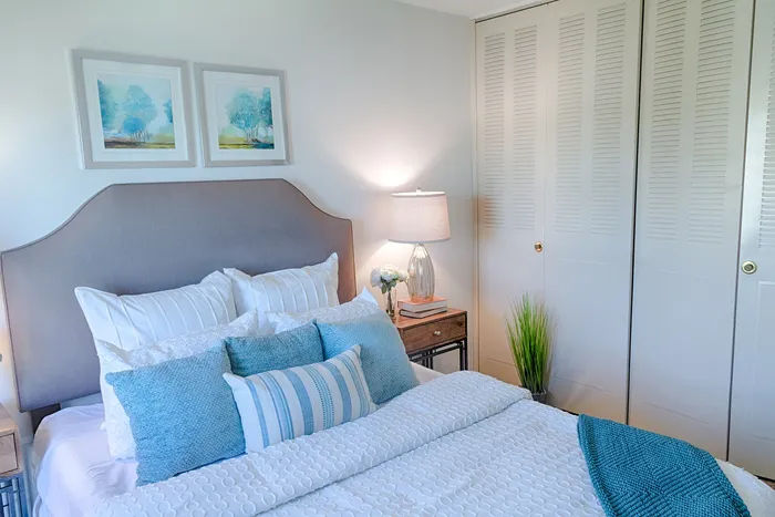 Bright and cozy bedroom featuring elegant decor, a plush bed with stylish pillows, and modern artwork on the wall.