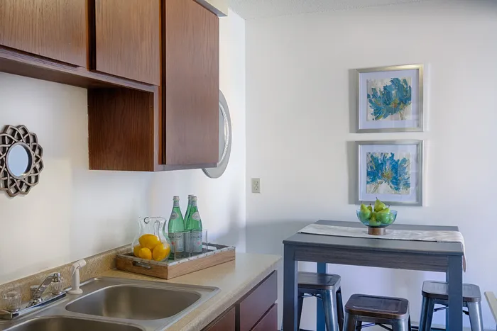 Chic kitchen corner with wooden cabinets, vibrant artwork, and a cozy dining area showcasing modern decor.
