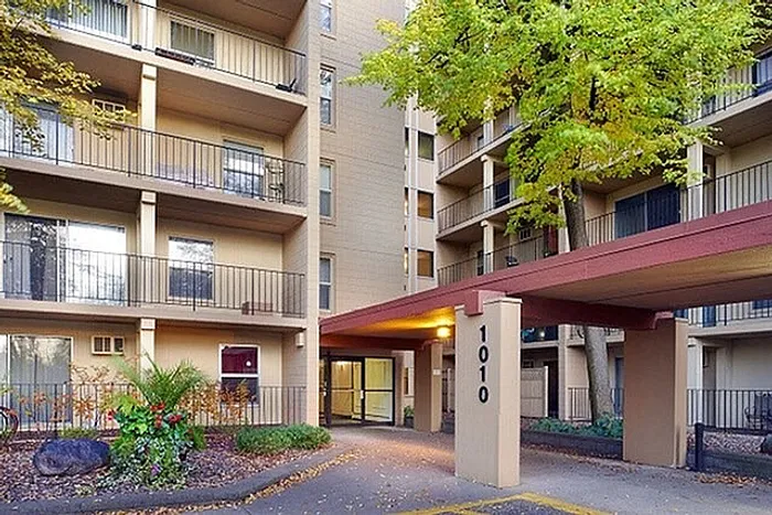 Charming apartment building facade adorned with lush greenery, featuring spacious balconies and a welcoming entrance at 1010.