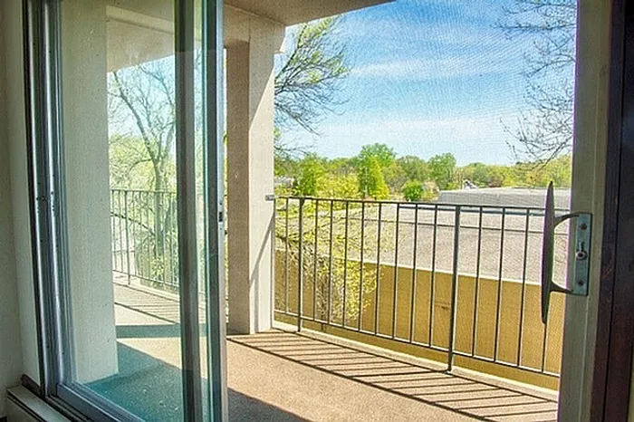 Bright and inviting balcony with a scenic view, featuring elegant railings and glass sliding doors.