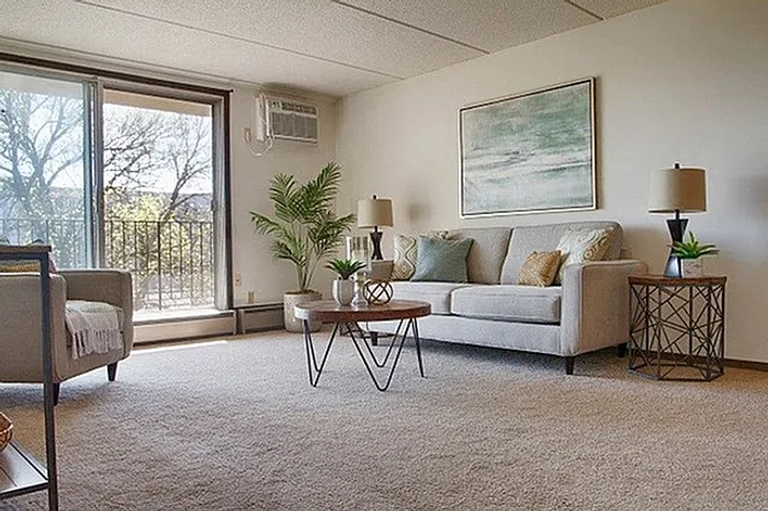 Bright and cozy living room with modern decor, featuring a plush sofa, stylish coffee table, and large sliding glass doors opening to a scenic balcony view.