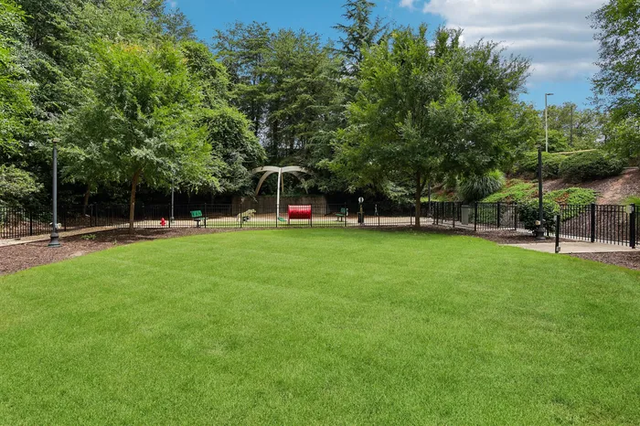 Vibrant community park with lush green lawn, mature trees, and inviting seating area, perfect for relaxing outdoors.