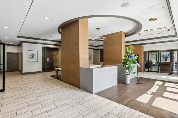 Elegant apartment lobby with modern design, featuring sleek wood accents, contemporary lighting, and a vibrant indoor plant.