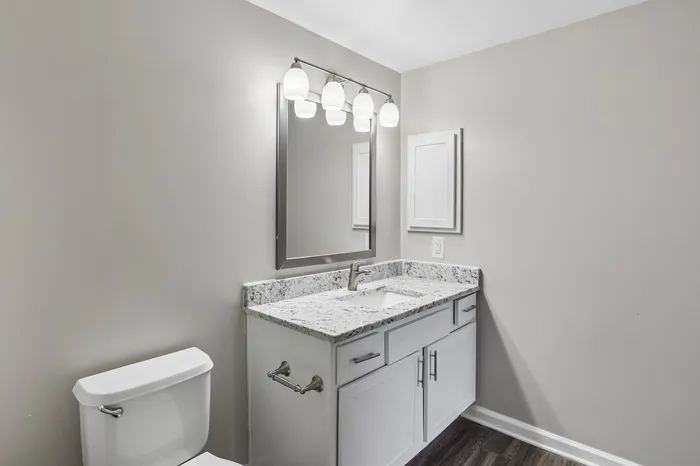 Sleek bathroom with modern vanity, granite countertop, and designer lighting.