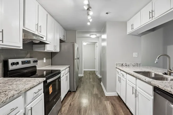 Modern kitchen with elegant granite countertops, sleek stainless steel appliances, and ample white cabinetry, creating a bright and inviting space.