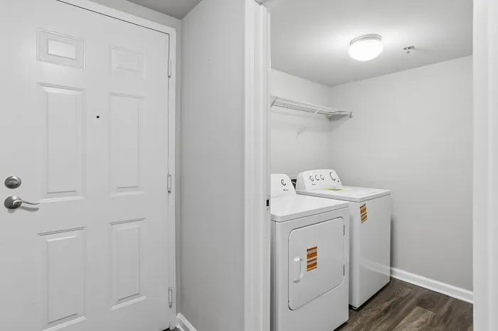 Bright laundry room with modern washer and dryer, featuring sleek shelving and elegant wood flooring.