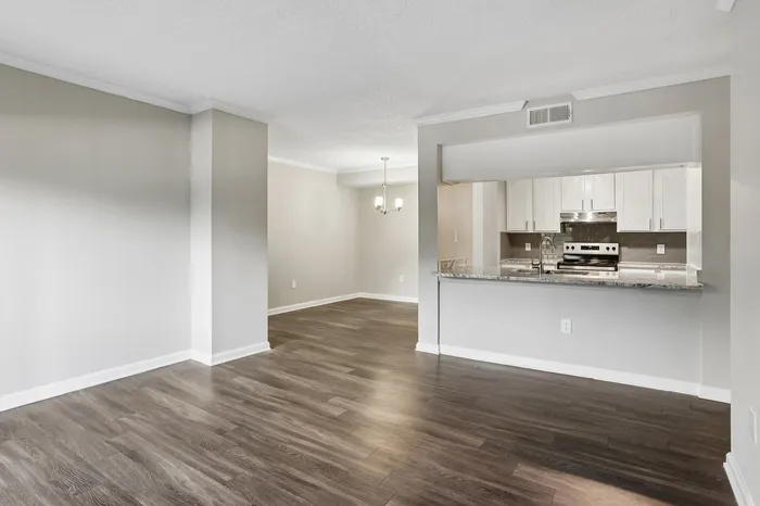 Modern open-concept apartment with elegant hardwood floors, a stylish kitchen featuring white cabinetry, and a cozy dining area with chic lighting.