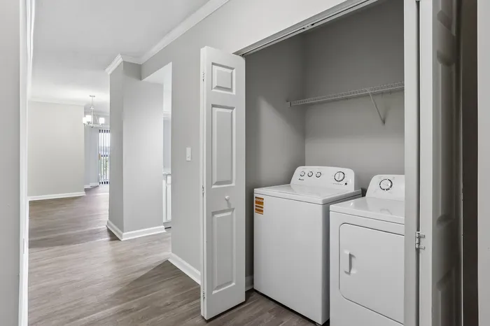 Modern apartment with a sleek open layout, featuring a convenient in-unit laundry area adjacent to a bright dining space with hardwood flooring.