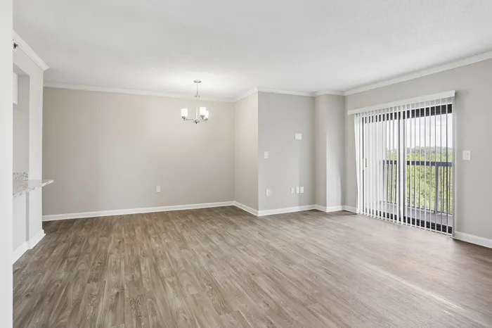 Bright and airy living room with elegant hardwood floors, modern chandelier, and large sliding glass doors leading to a scenic balcony view.