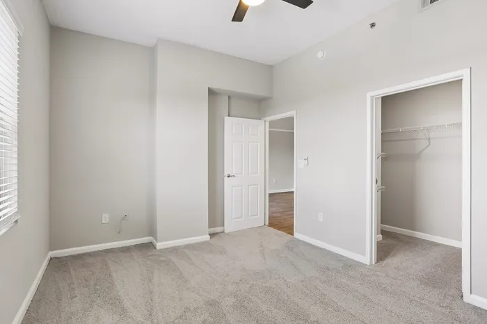 Bright, spacious bedroom with plush carpeting, ample closet space, and modern ceiling fan.