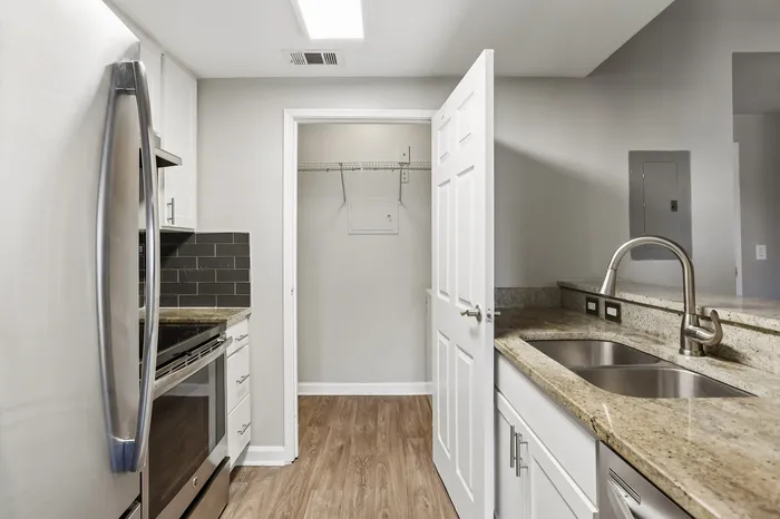 Modern kitchen featuring stainless steel appliances, sleek granite countertops, and elegant cabinetry with a convenient pantry space.