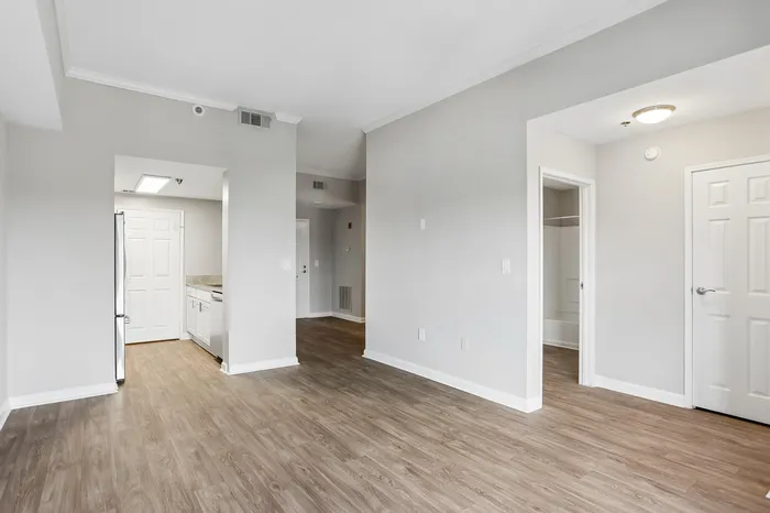 Bright and airy living space with stylish wooden flooring, crisp white walls, and modern kitchen entry creating an inviting atmosphere.