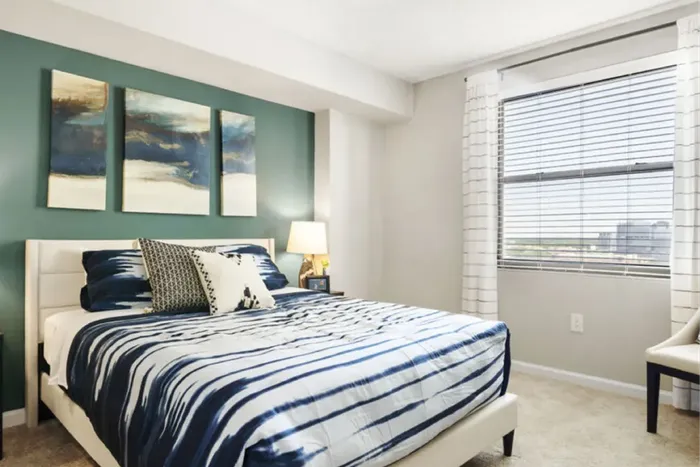 Bright and modern bedroom featuring chic decor, a stylish striped bedspread, and a large window with scenic views.