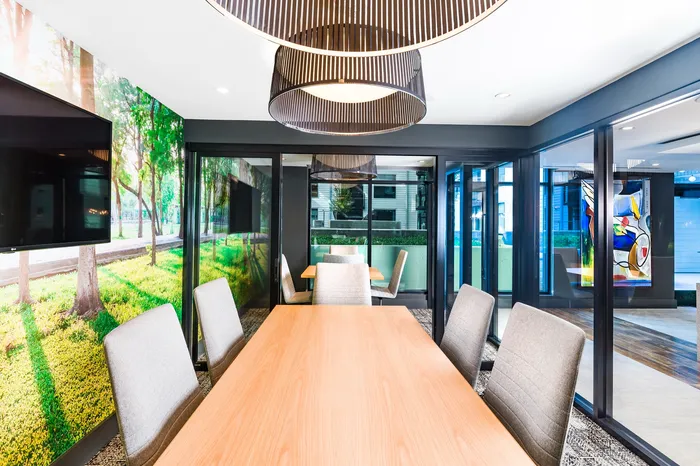 Modern meeting room with sleek wooden table, comfortable chairs, large windows, and vibrant wall art.