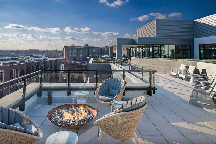 Luxurious rooftop terrace featuring modern patio furniture and a stylish fire pit with stunning city views.