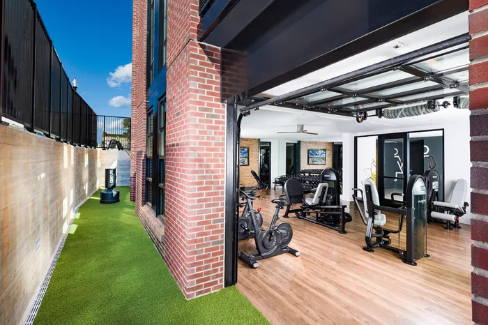 Modern fitness center with state-of-the-art equipment and sleek design, featuring large windows and vibrant outdoor green space.