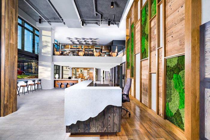 Modern open-space commercial interior with wooden accents, vibrant green wall features, and ample natural light.