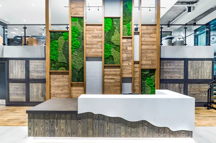 Contemporary interior with a stylish moss wall and rustic wood paneling behind a modern reception desk.