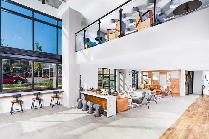 Bright, modern living space with floor-to-ceiling windows, stylish seating, and sleek wooden flooring, perfect for social gatherings.