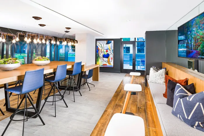 Modern communal lounge with sleek wooden flooring, vibrant artwork, and stylish seating areas perfect for relaxation and social gatherings.