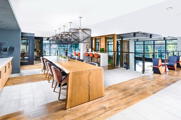 Modern, open-concept lounge area featuring elegant wooden flooring, chic pendant lighting, and ample seating with a view.