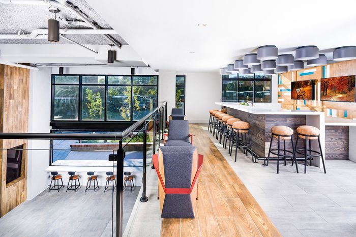 Modern communal space featuring a sleek bar area with stylish seating, large windows for ample natural light, and contemporary decor.