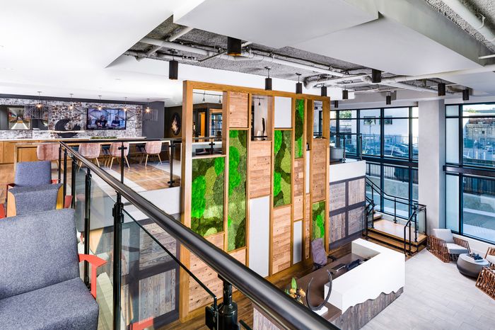 Modern apartment interior with open-plan communal area featuring elegant wooden accents, lush green vertical garden, and panoramic windows for abundant natural light.