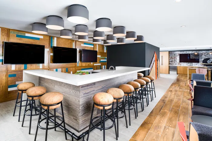 Modern lounge area with sleek bar, stylish wooden stools, and contemporary lighting fixtures.