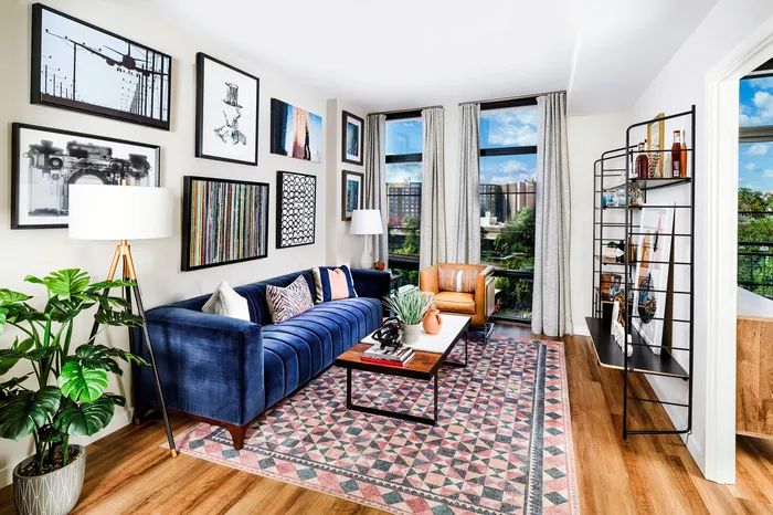 Chic living room with vibrant art pieces, plush blue sofa, and floor-to-ceiling windows offering stunning views.
