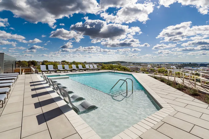 Luxurious rooftop pool with chic lounge chairs and stunning skyline views, perfect for a refreshing escape.