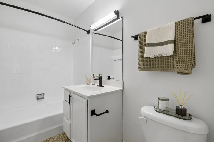 Bright and modern bathroom featuring a sleek white vanity, elegant towel rack, and fresh, clean decor.