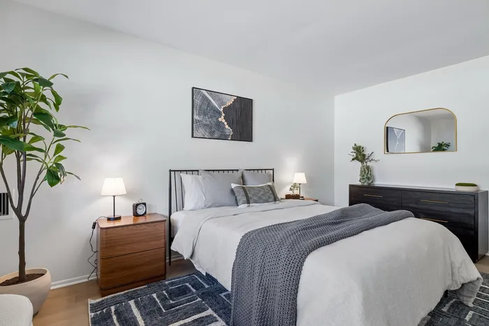 Elegant bedroom boasting a cozy bed with stylish bedding, modern wooden furniture, and chic decor, complemented by a lush indoor plant and soft ambient lighting.