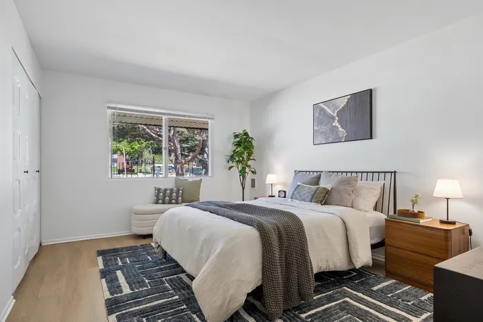 Elegant bedroom featuring a cozy double bed with plush cushions, stylish decor, and a large window offering abundant natural light.