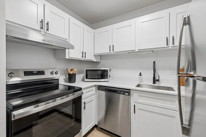 Modern kitchen with sleek stainless steel appliances, elegant white cabinetry, and stylish black fixtures.