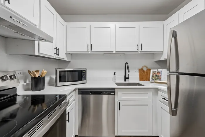 Modern kitchen with sleek stainless steel appliances, white cabinetry, and chic black fixtures.