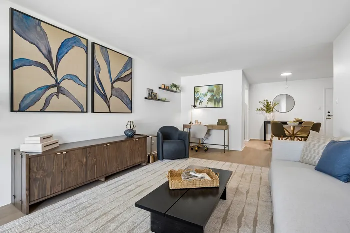 Elegantly styled living room with modern decor, featuring a cozy workspace, chic dining area, and artistic wall paintings.