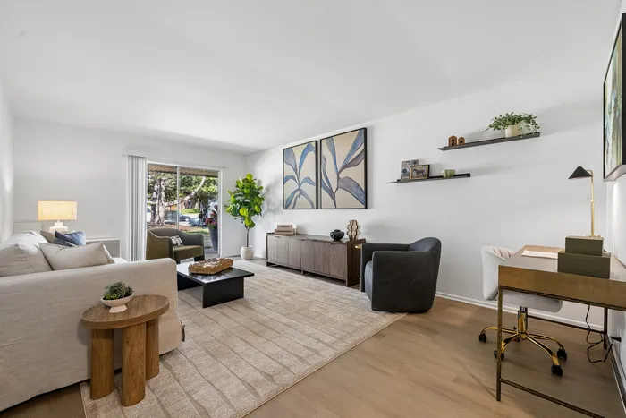 Bright and modern living room with elegant decor, featuring a cozy sofa, stylish armchair, and large window with a view of lush greenery.