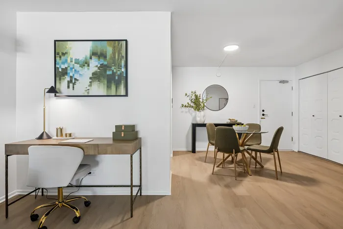 Modern apartment interior with a sleek workspace, elegant art, and a chic dining area showcasing contemporary design.