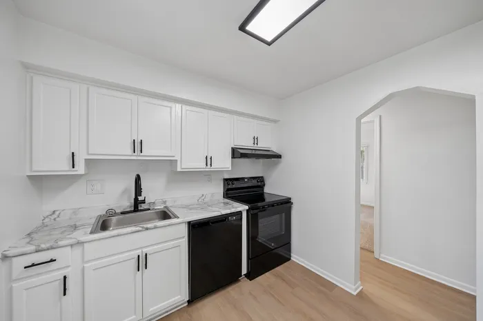 Modern kitchen with sleek black appliances, marble countertops, and chic white cabinetry offering a stylish and functional space.