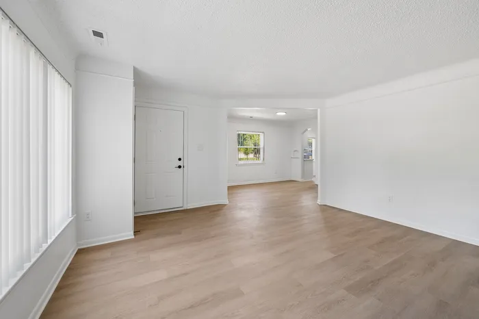 Bright and inviting open-plan living area with modern hardwood floors, abundant natural light, and a seamless flow from entryway to spacious room.