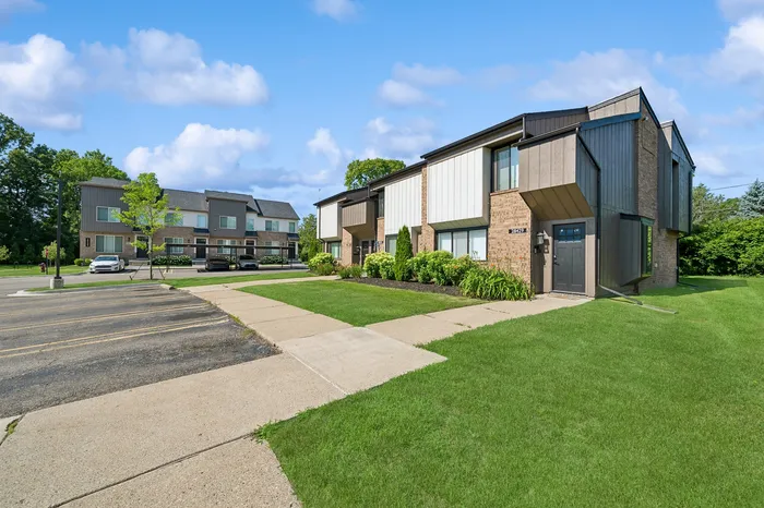 Modern townhouse complex with lush green lawns and blue skies creating a welcoming community atmosphere.