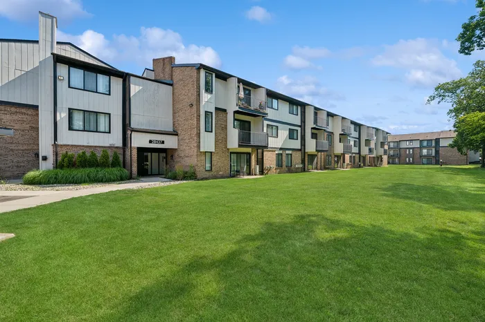 Charming three-story apartment building with modern design, featuring spacious outdoor green space and inviting balconies.