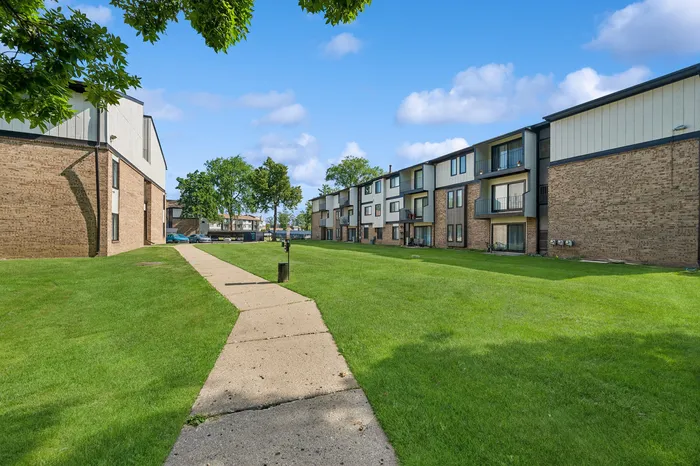Charming apartment complex surrounded by lush green lawns, offering a serene and inviting living environment.