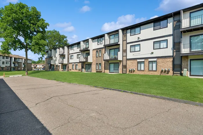 Charming multi-story apartment building with balconies and lush green surroundings.