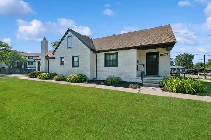 Charming white brick house with manicured lawns and inviting front entrance, set under a clear blue sky.