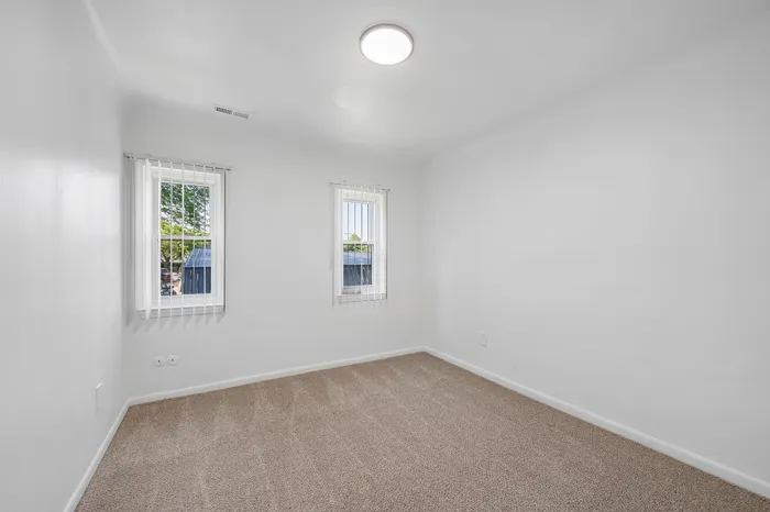 Bright and airy bedroom with plush carpet and large windows, offering a serene view and abundant natural light.