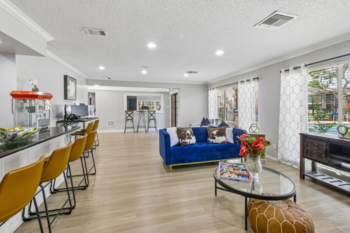 Bright and modern living area with vibrant blue couch, inviting bar seating, and large windows showcasing pool views.